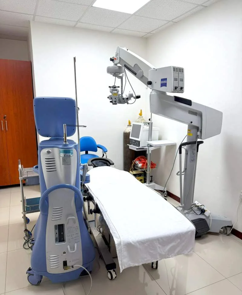 The sterile and technologically advanced surgical theater at Kampala Eye & Lasik Hospital, centered around a modern operating bed and microscope.
